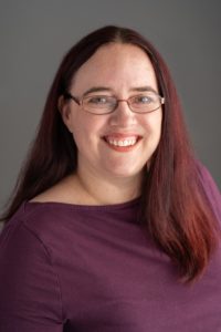 Picture of licensed psychologist in the Stockton-Lodi area of California Kimberlee DeRushia, PsyD. A white cisgender woman wearing glasses with auburn hair an a merlot colored top.